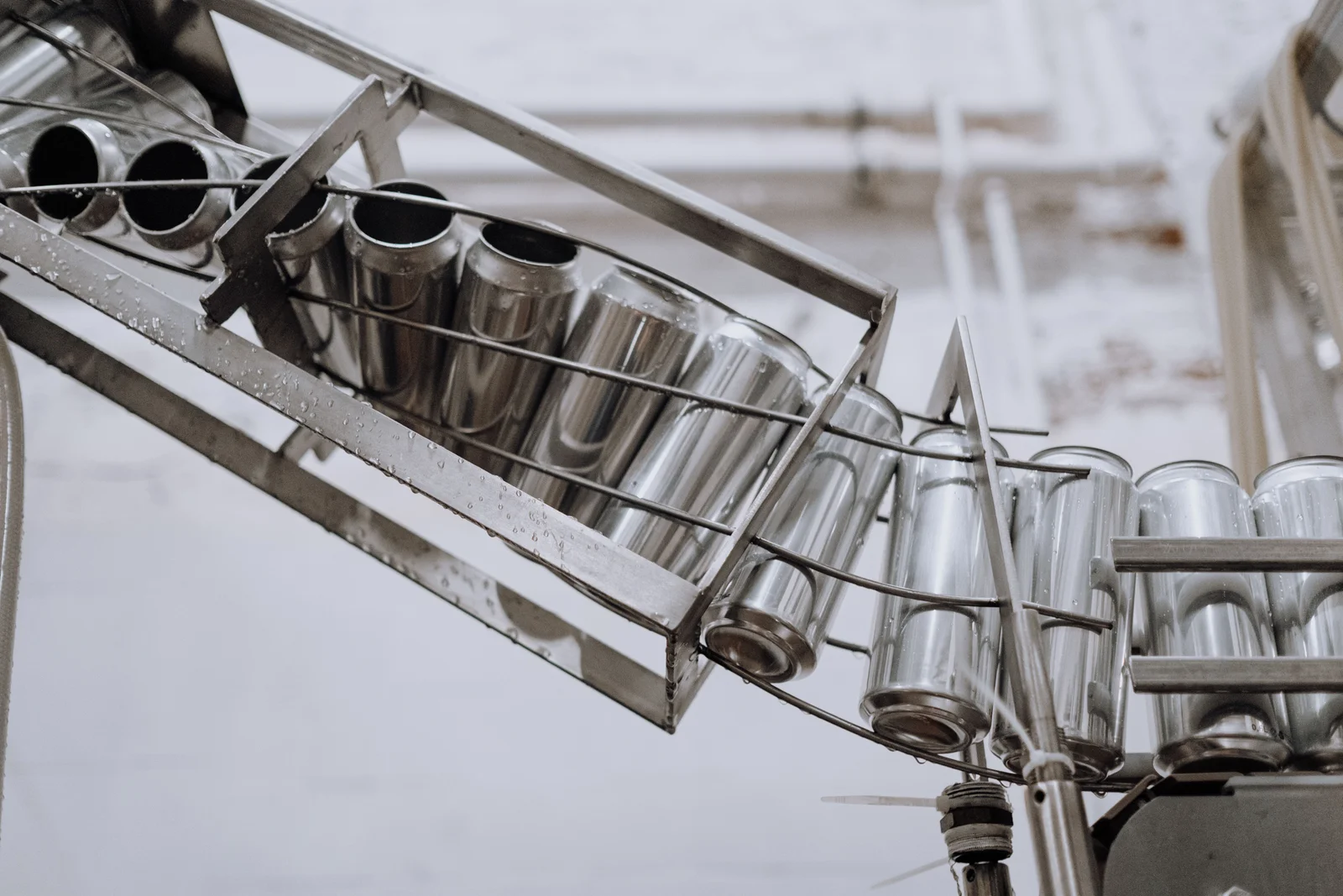Silver metal cans moving along a conveyor.